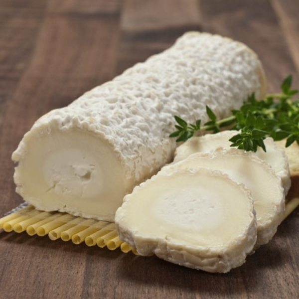 Log of creamy goat cheese with a textured rind, sliced to showcase its smooth interior, accompanied by fresh herbs on a wooden surface. Ideal for cheese boards and gourmet dishes.